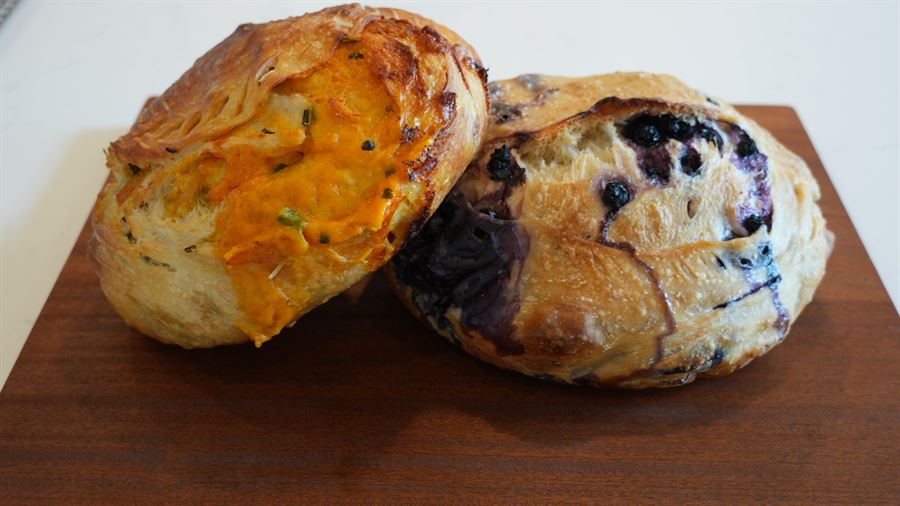 Two artisan sourdough loaves on a cutting board — jalapeño cheddar and blueberry lemon
